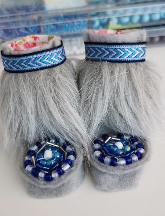 A miniature pair of felted boots. Grey felt with matching fur. Arrow patterned trim and round matching beads. Added a white and pink floral patterned liner for both