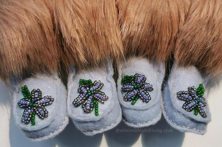 Two pairs of mukluk boots. Purple flowers and felt with light brown fur. Top stitch is visible on all pairs. The flowers are purple seed beads. Inside petals pearlescent with metallic outline and green beaded stems.