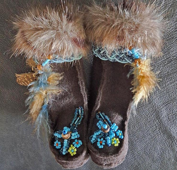 Brown felt boots with feathers. The vamps have three flowers in blue and green bead. A topstitch runs down the front, and a blue braided trim for texture. The brown synthetic fur is dyed with reddish streaks.